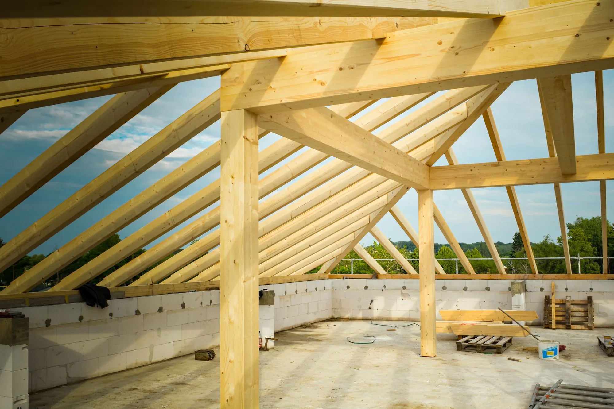 New timber roof trusses standing over an unfinished house against the sky