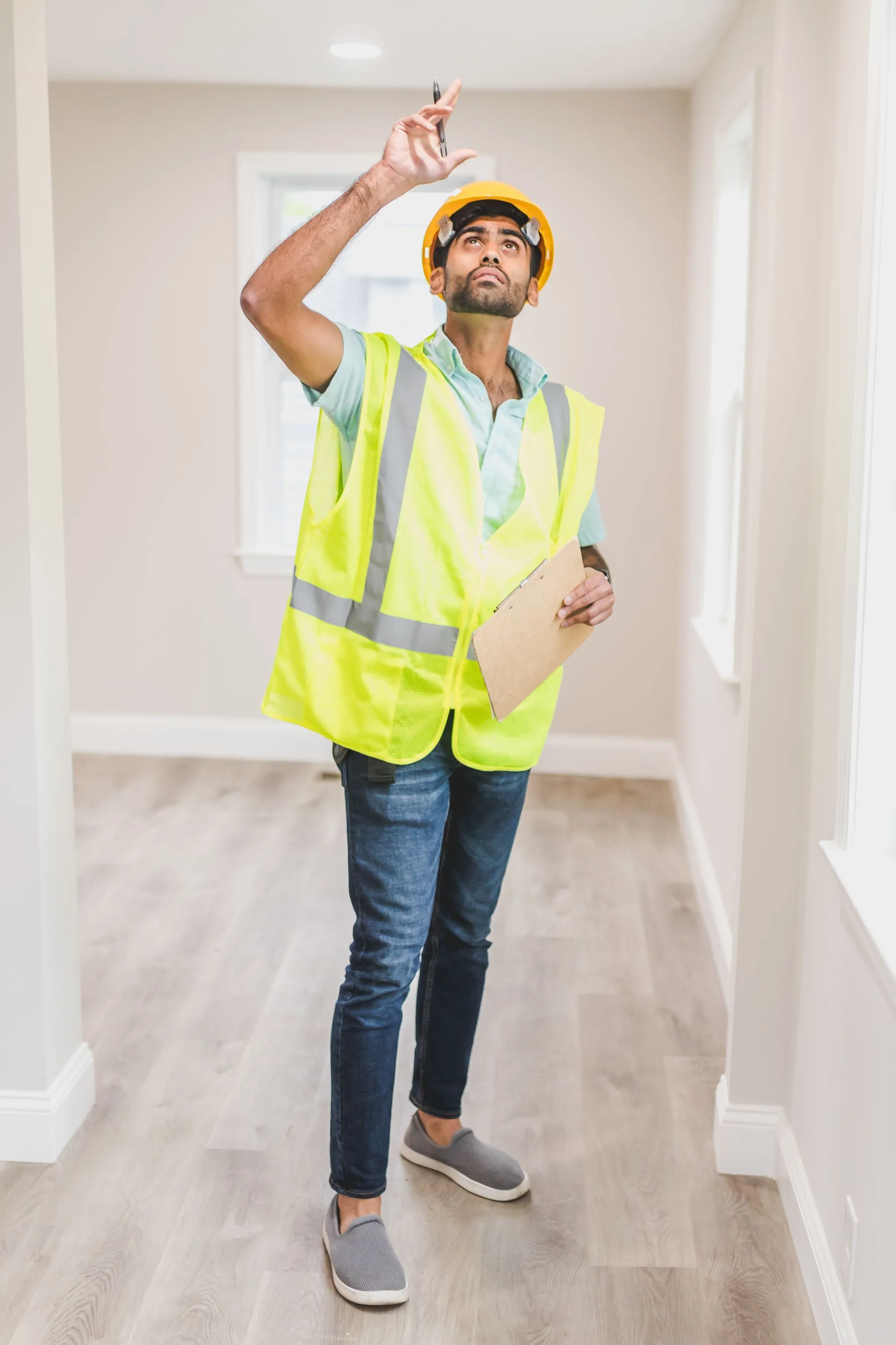 An inspector in a high-visibility vest making notes on a clipboard indoors
