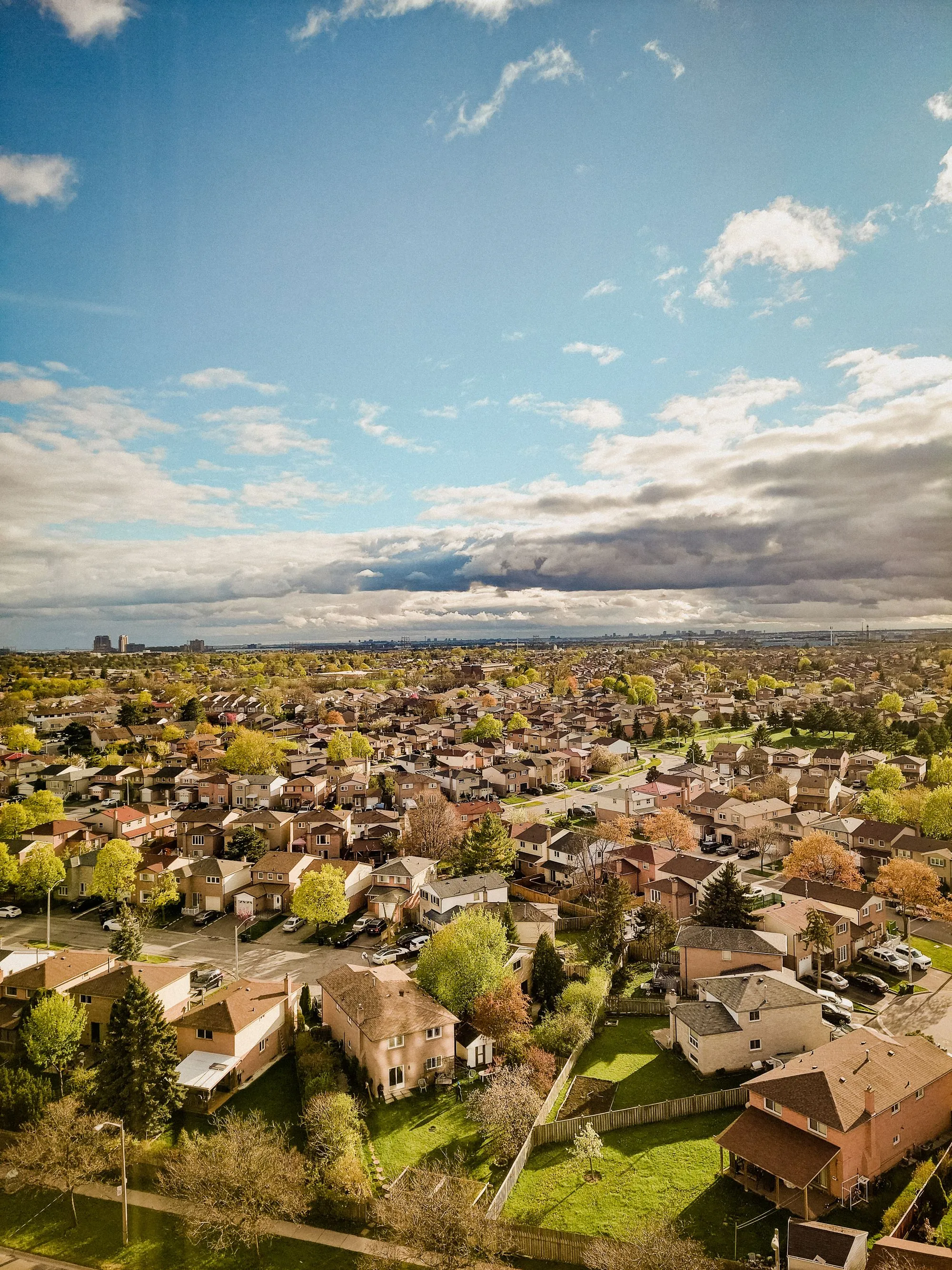An aerial view of a suburban township of pitched roofs under broken cloud