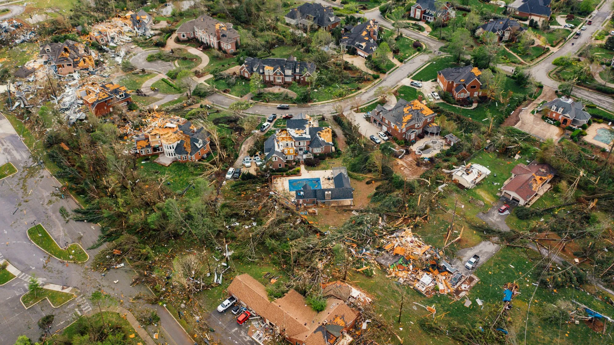 An aerial view of a neighbourhood with roofs torn open after a storm