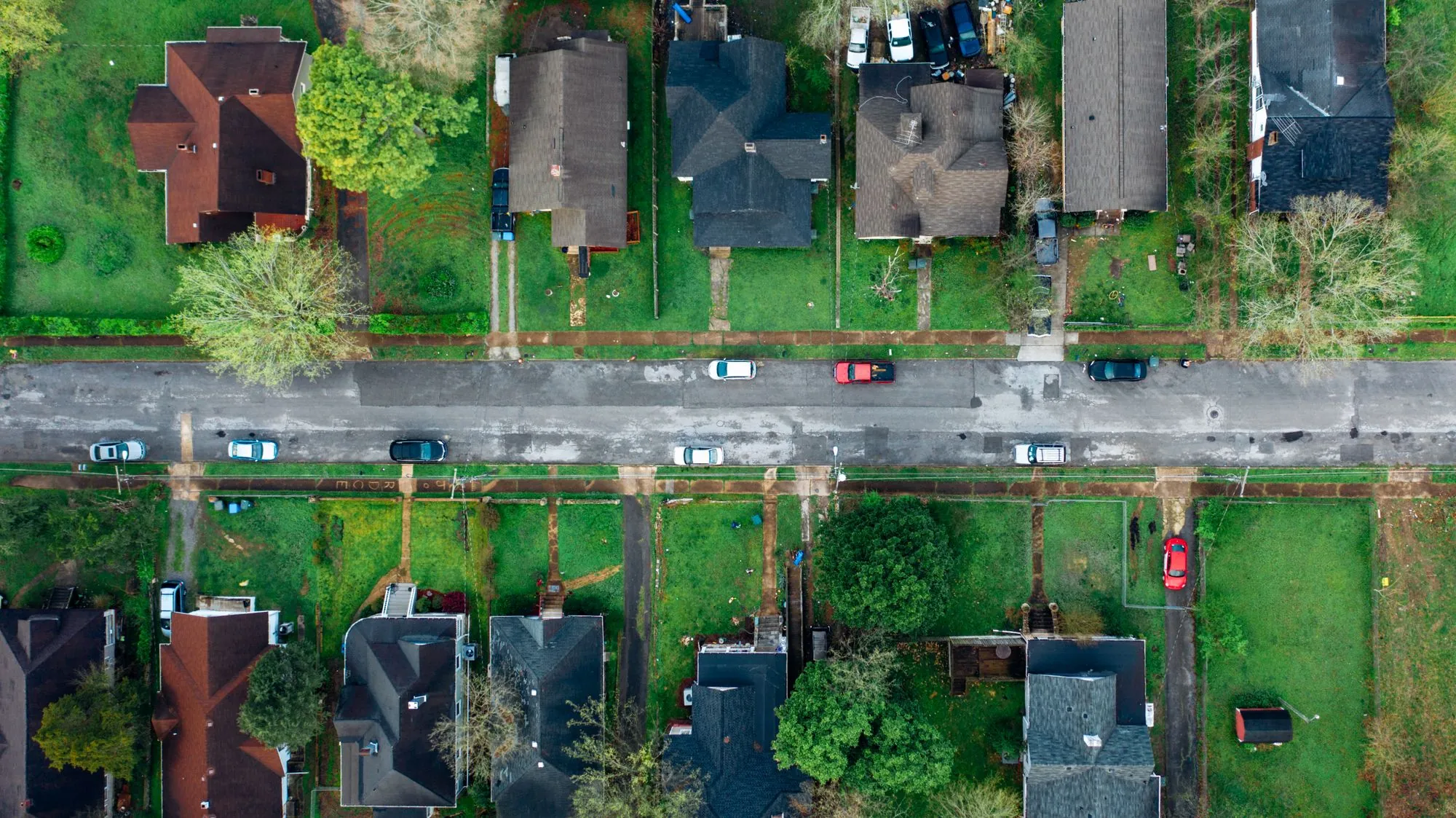An overhead view of a residential street, its roofs and back gardens